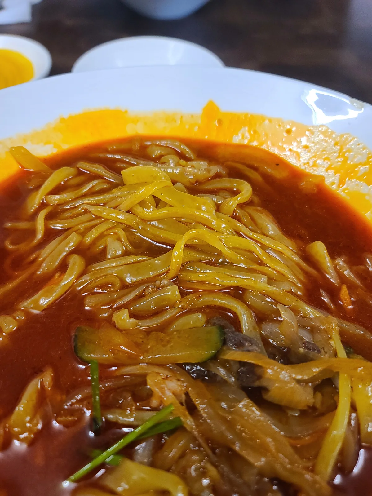 Close-up of wide ongsimi noodles in red jjamppong broth
